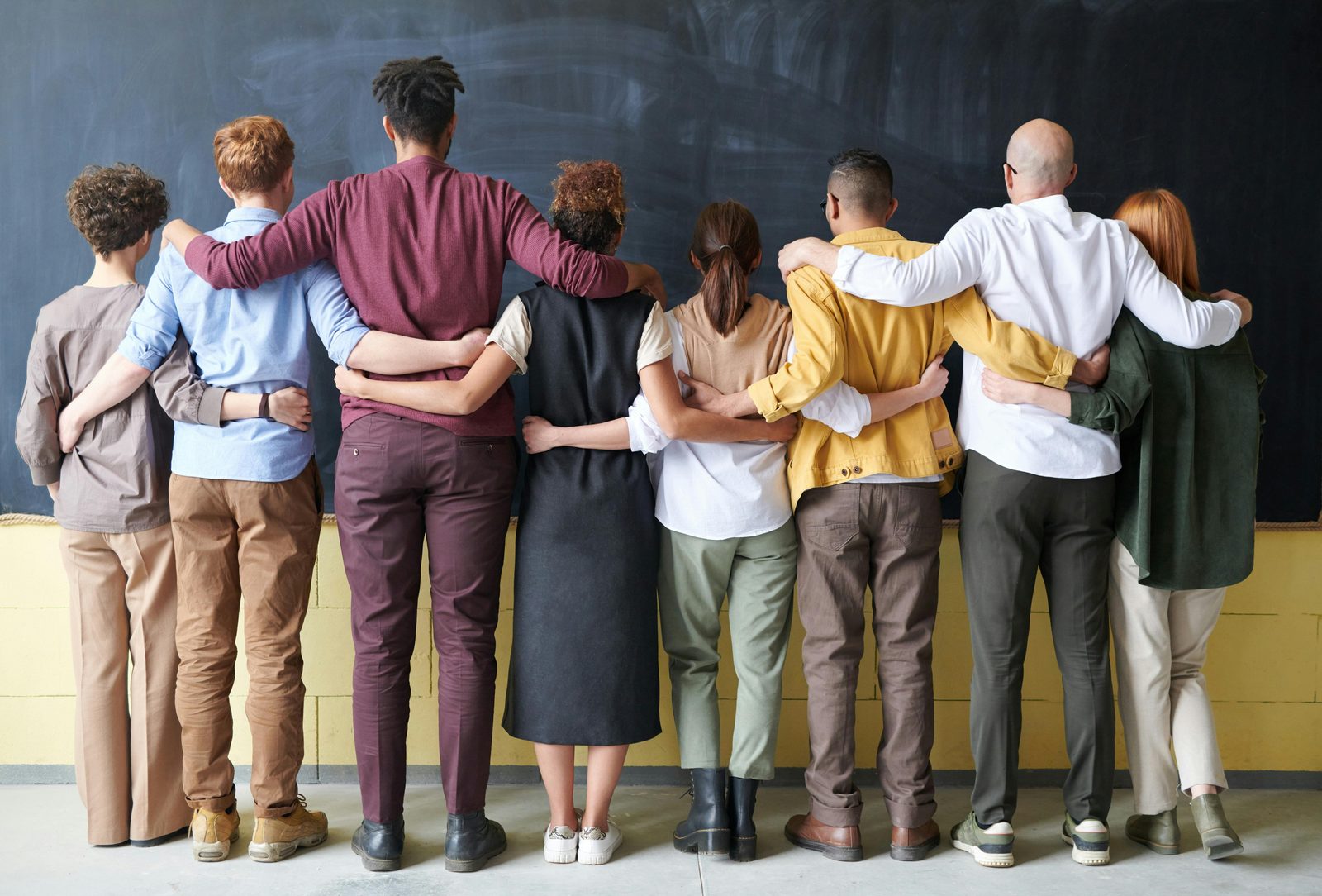The adnah labs team standing arm in arm facing a chalkboard wall